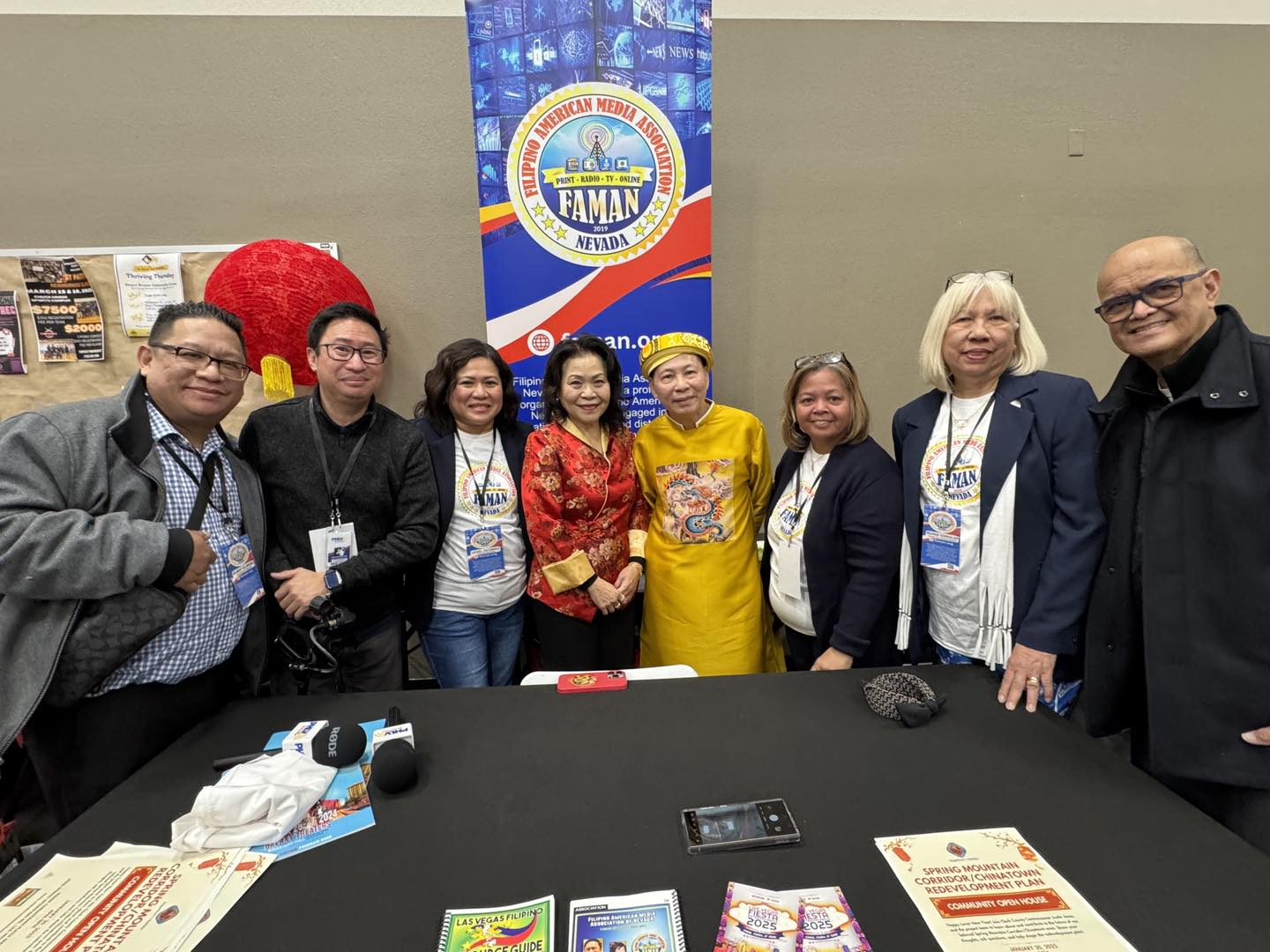 A group photo of members from the Filipino American Media Association of Nevada (FAMAN) standing alongside Vietnamese community leaders. The individuals are smiling warmly, with the FAMAN banner prominently displayed in the background. The image captures a moment of unity and collaboration, emphasizing the partnership between the Filipino-American and Vietnamese-American communities at the Tết Festival. Traditional Vietnamese and professional attire further showcase the cultural and formal essence of the event.